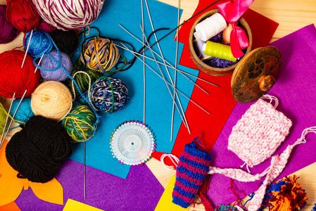 彩色拼贴织物。 多色线毛球。 家用针织用针织针。 带有线轴和针线的棺材用于缝纫。 木制背景上的静止生命。