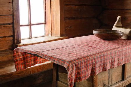 一个古老的农家木屋的内部碎片一张桌子，上面有木制的盘子和手工编织的桌布