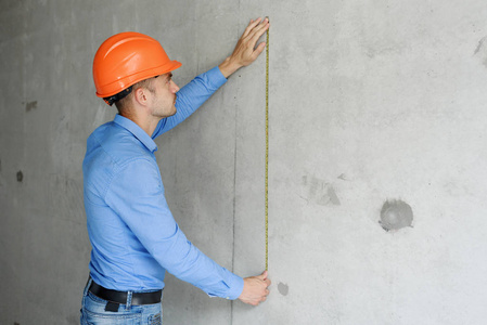满意的建筑工人工头测量在建房屋的墙参数的磁带测量.