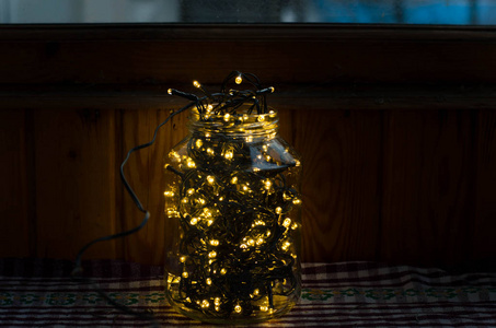 圣诞灯。 装饰灯。 温暖的白色LED灯。 在黑暗中，一个格子桌布上的罐子里的圣诞灯装饰品。