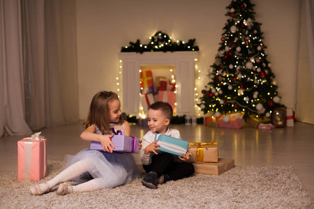 一个男孩与一个女孩打开圣诞礼物新年假期加兰灯