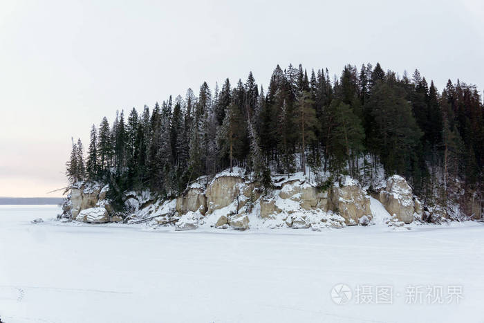 冬天的风景，冰冻的河流上有一个多岩石的木岛