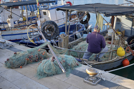  fisherman cleaning his nets on a fishing boat in the port 