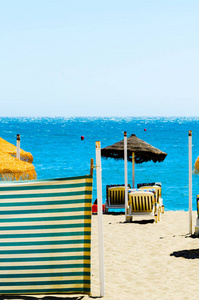 美丽的沙滩，有棕榈树伞和蓝海度假
