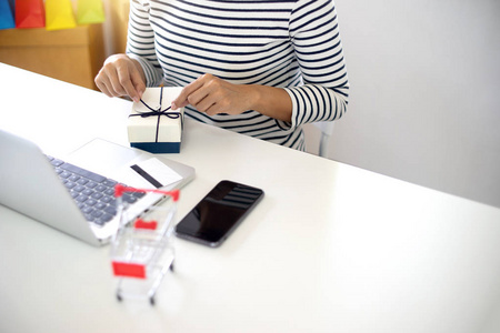 女人坐在电脑桌前看产品包装打开或包装主题购物网上销售和购买订单