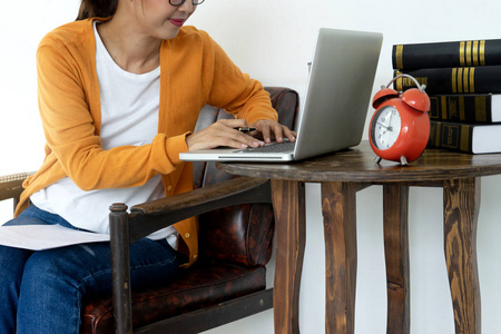 妇女在家工作，她的电脑和纸笔使用互联网在房间工作的在线风格。
