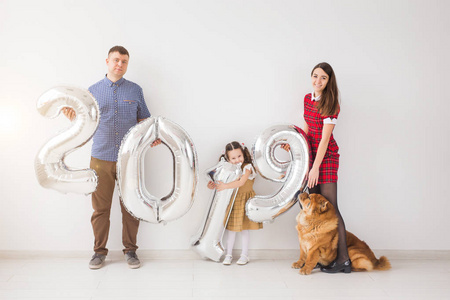 新的2019年即将到来的概念快乐的家庭与狗是举行银白色数字在室内