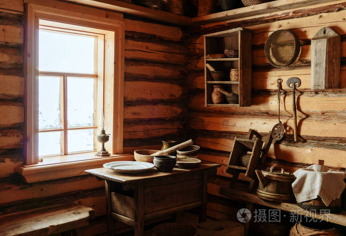 一个老农木木屋的内部碎片一张桌子上面有木制和陶瓷盘子还有煤油灯