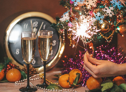 clock, glasses of champagne with bubbles, sparklers in the hand 