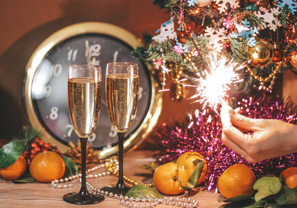 clock, glasses of champagne with bubbles, sparklers in the hand 