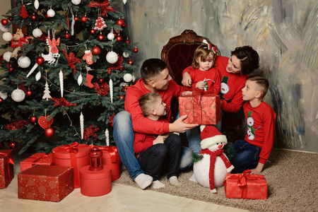 一个有趣的年轻家庭坐在圣诞树旁,带着礼物2照片