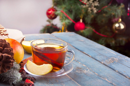 热饮苹果茶与肉桂棒八角茴香和丁香。 季节性苹果打孔杯在木制背景上。