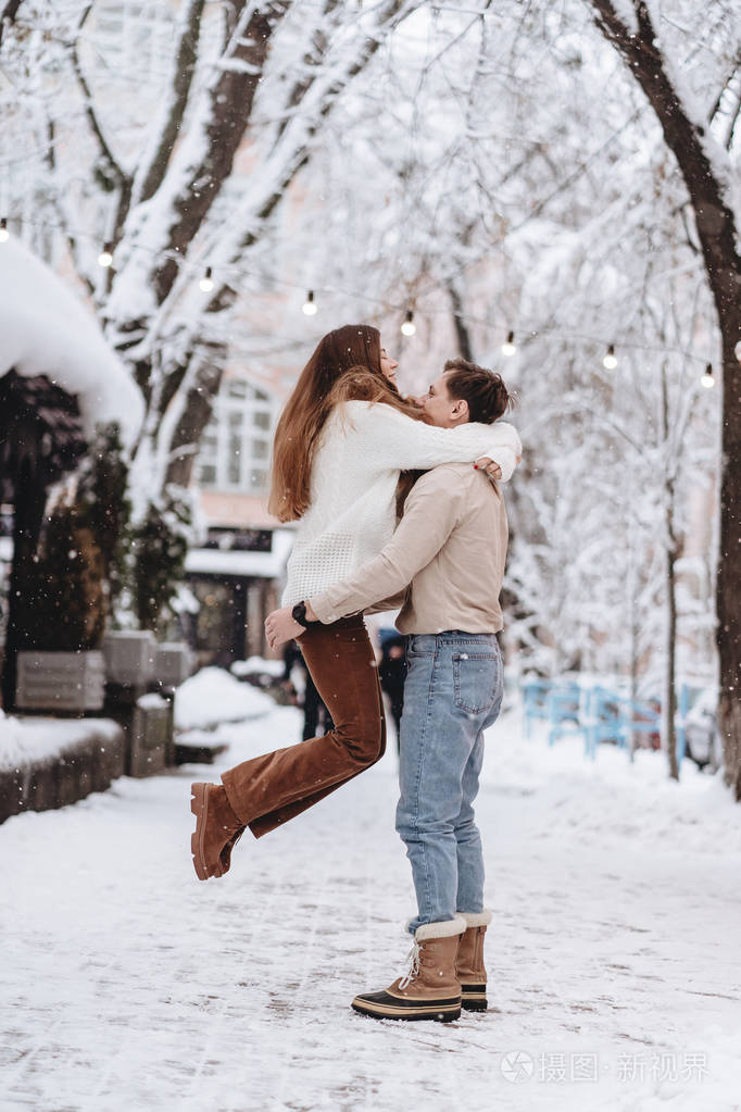 年轻人抱着一个漂亮的女孩情侣穿着毛衣