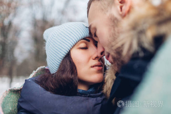 在冬天的森林里美丽的情侣拥抱着互相看着对方的眼睛人们用毯子取暖