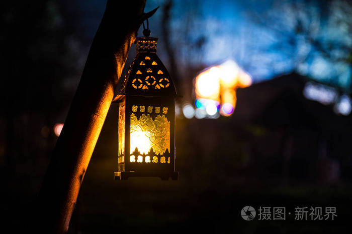 雾蒙蒙的夜晚,花园里美丽的彩色照明灯. 复古风格的灯笼在夜间户外. 