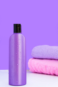 一个紫色化妆瓶和两条浴巾，用于水疗身体和头发护理