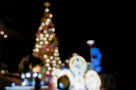 在城市的圣诞夜，圣诞树的模糊和弯曲的景色和装饰LED照明商场的前面。