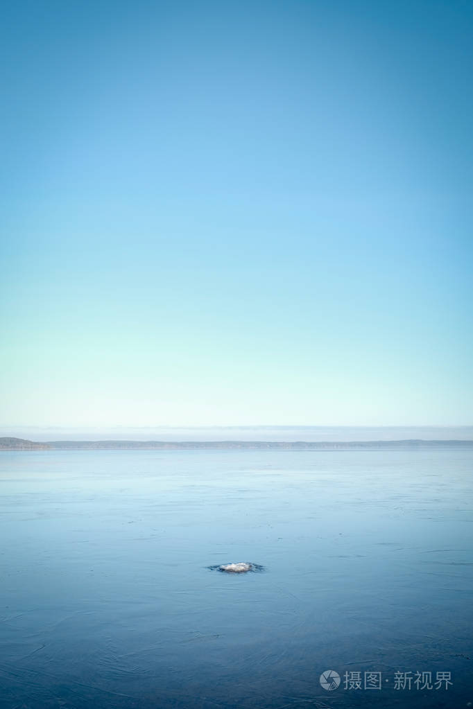 蓝色的天空中没有云的湖面上的冰雪小圆岛