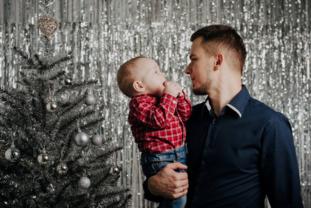 儿子和爸爸。一个小男孩在他父亲的怀里在圣诞树上