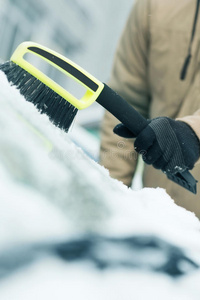 男子用刷子清除汽车挡风玻璃上的积雪