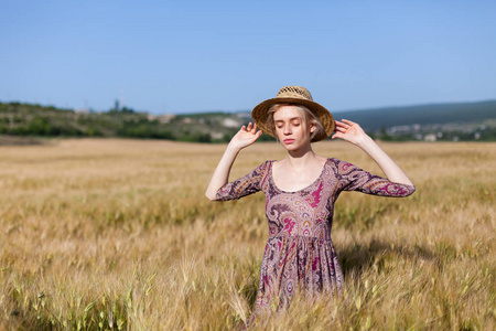 一个戴帽子的女农民在成熟的小麦收获领域
