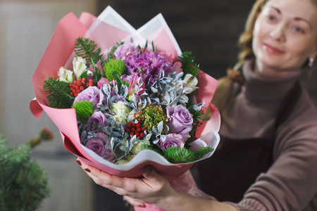 穿着棕色围裙的女花店向买家展示了一束美丽的鲜花，作为婚礼或周年纪念的节日礼物。
