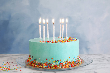 四个彩色的生日蜡烛新鲜美味的生日蛋糕,桌子上有蜡烛,背景是彩色的