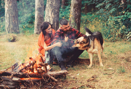 夫妇与德国牧羊犬在篝火旁玩耍