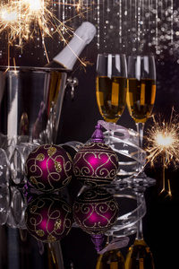 两个酒杯，香槟瓶，桶火花和圣诞装饰品在黑色背景。 复制空间。 圣诞快乐，新年快乐