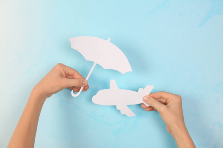 妇女覆盖纸飞机与伞切割在颜色背景特写。 旅行保险概念