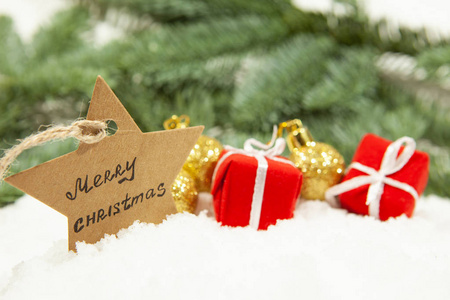 一颗铭刻着圣诞快乐的星星，以及在白雪上戴着球的礼物