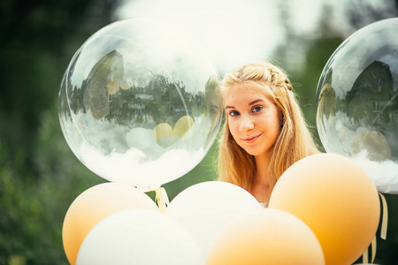 在自然背景上有气球的年轻女孩的肖像。