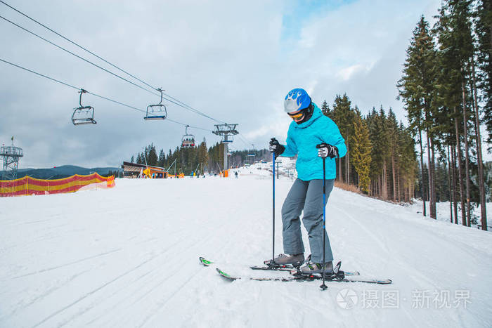 年轻的成年女人滑雪。 白雪皑皑的小山，背景上有电梯。 冬季体育活动