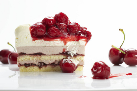 以白色奶油和樱桃为装饰的甜而美味的蛋糕，分离在白色背景上