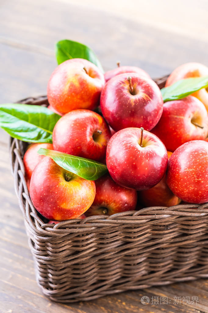 桌子上棕色篮子里有很多红苹果水果