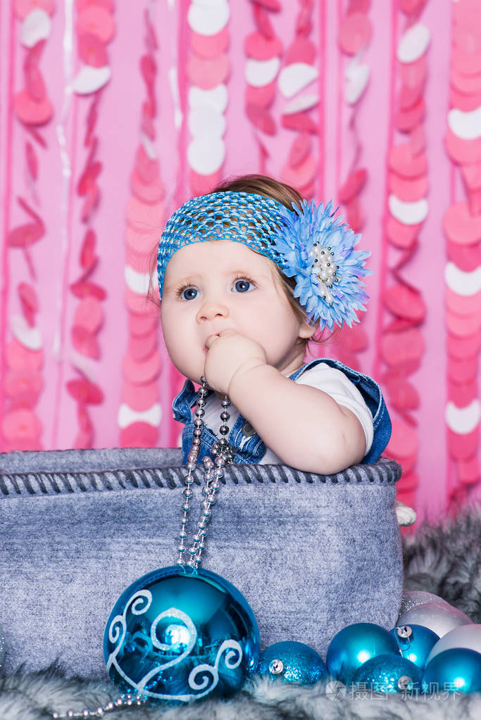 小女孩,蓝色的大眼睛,穿着蓝色的牛仔裙和蓝色的花弓,坐在一个柔软的