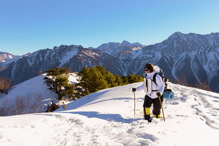 在阳光明媚的日子里，带着装备的年轻女孩山区游客在冬天穿过卡拉恰伊谢尔凯西亚山脉的大雪。