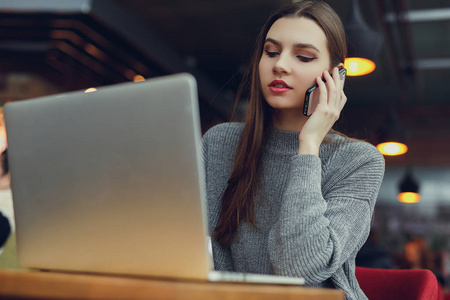 往下看。 年轻的商务女性坐在桌子旁，一边看着笔记本电脑，一边看着她的手机。 在咖啡馆工作的女人。 博客。 图像