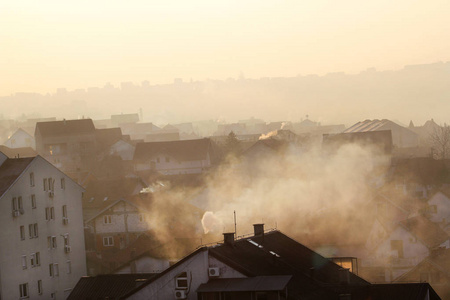 屋顶吸烟的烟囱在日出时排放烟雾，污染物进入大气。 环境灾难。 有害排放和废气进入空气。 雾冬天采暖季节。