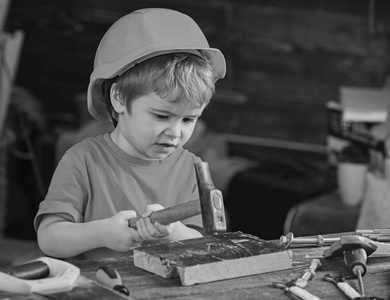 集中的孩子用锤子工作。小男孩获得新的技能。儿童学习锤钉