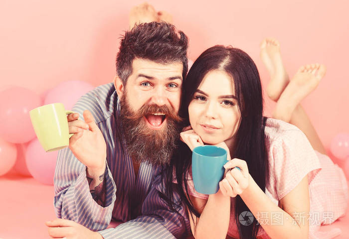 男人和女人面带微笑, 粉红色的背景.情侣们早上喝咖啡放松一下.