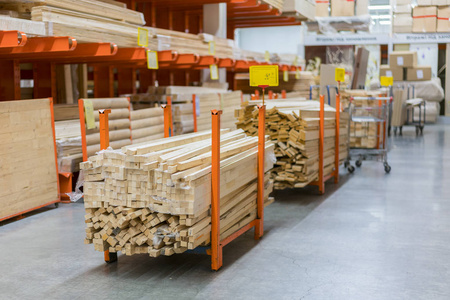 在美国大型五金店的木材堆场内堆放新的木条。仓库内用平板车和手动叉车堆放新磨坊或切割木材