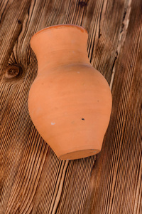 木制桌子背景上手工制作的陶瓷壶或水壶。