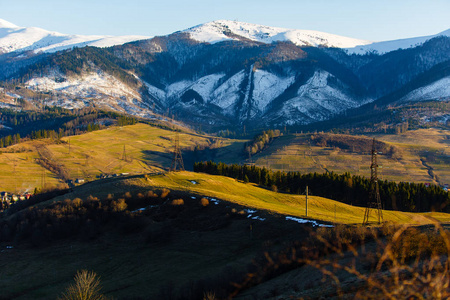 雪山和绿色的山底。早春。美丽的风景