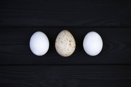 鹅蛋和鸡蛋在黑色的木制背景上。 各种鸟类卵大小的差异。