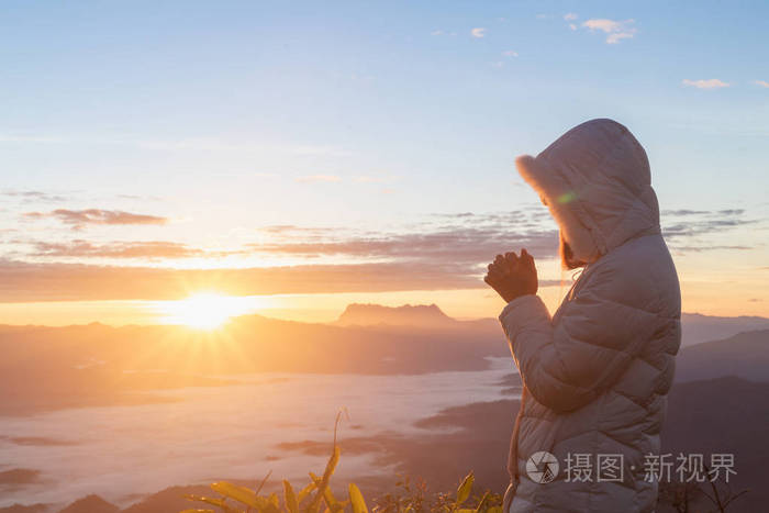 基督教妇女手祈祷上帝在山上的背景与早晨日出女人祈求上帝的祝福希望