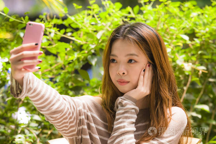 学生女孩用手机相机拍摄自拍肖像照片,互联网社交媒体在花园外摆姿势