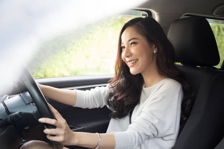 亚洲女性开车，在旅途中开心地微笑，开心地积极地表达着快乐的表情，人们在旅途中享受着欢笑的交通和轻松的快乐女人的度假理念