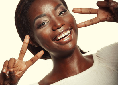 非洲裔美国妇女微笑着看着相机显示手指做胜利标志