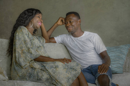 年轻有魅力快乐的黑人非裔美国人夫妇放松在家沙发沙发上聊天，一起甜蜜地享受，在爱中微笑着享受美丽的关系
